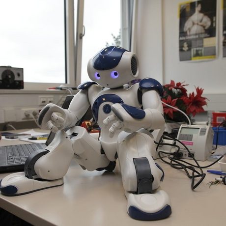 Ein kleiner Roboter sitzt auf einem Schreibtisch.