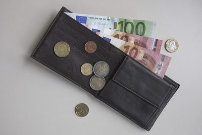 Aufnahme eines Geldbeutels mit Scheinen und Münzen von oben.